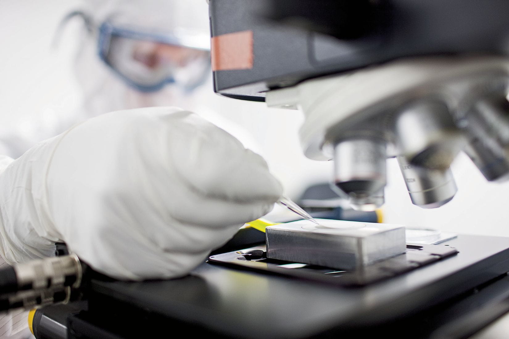 West scientist using a microscope in a lab, representing focus on quality and regulatory excellence.